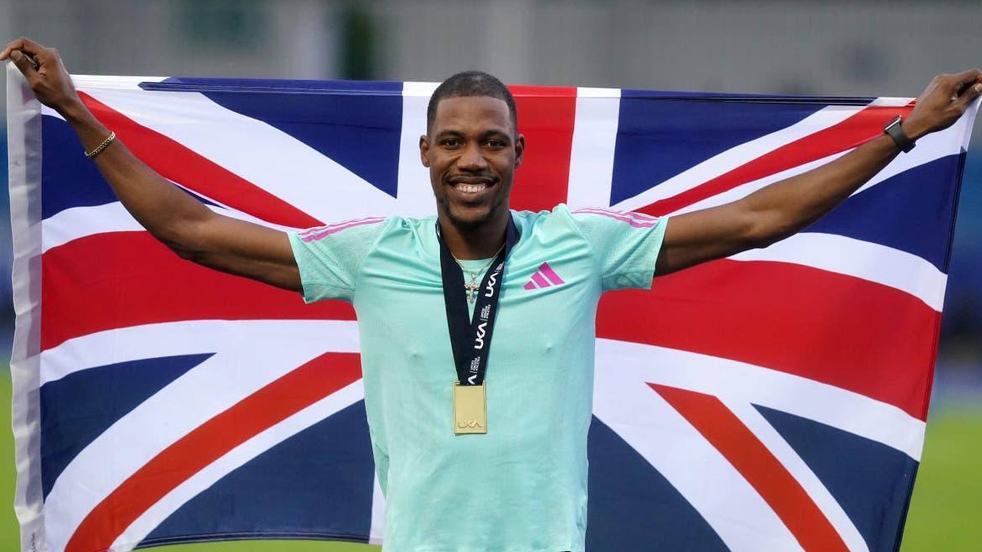 Zharnel Hughes holding the Great Britain flag (Image Credits - Twitter)